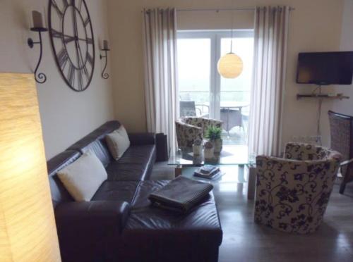 a living room with a black leather couch and a chair at Ferienhaus "Schöne Aussicht" in Neue Tiefe Fehmarn