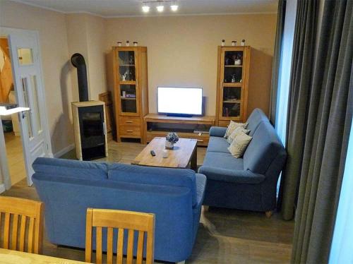 a living room with two blue couches and a tv at Haus Wellenkamp in Burg auf Fehmarn