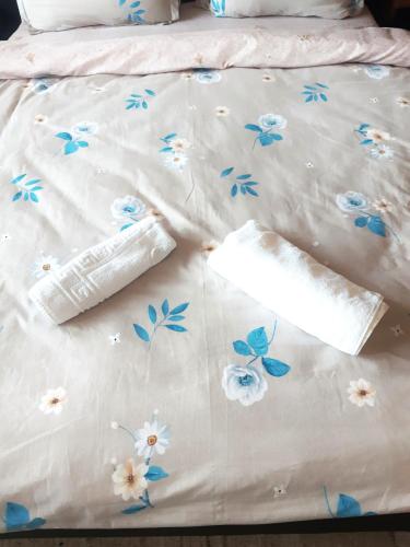 a bed with white sheets with blue flowers on it at Cozy Studio East-Side in Cluj-Napoca