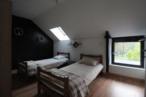 two beds in a room with a window at Maison en pierre 4 chambres 