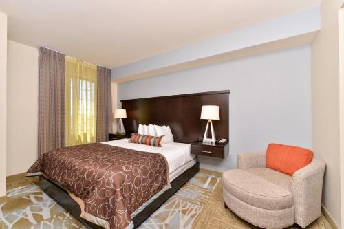 a hotel room with a bed and a chair at Staybridge Suites San Antonio-Stone Oak by IHG in San Antonio