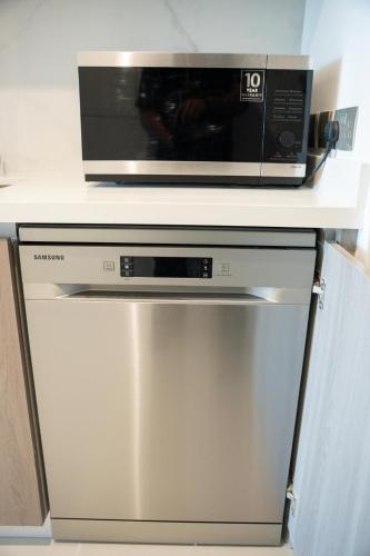 a microwave oven sitting on top of a dishwasher at Luxury Yas Golf Studio Next to Yas Parks in Abu Dhabi