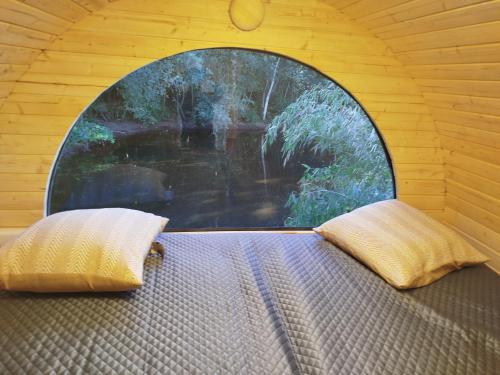 a window in a room with a bed with two pillows at Schlaffass Natursee-Chalet mit Sanitärfass in Twist