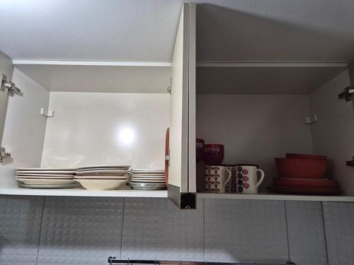 a kitchen cabinet with plates and bowls in it at Bangalô duplex 602 - Riviera do Atlântico in Conde