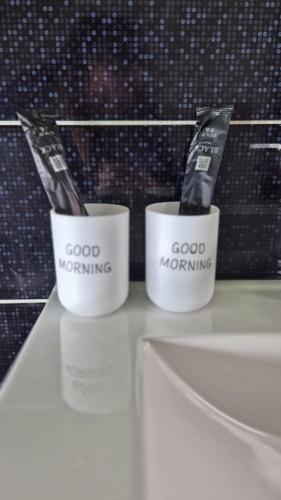 two white cups with toothbrushes in them on a counter at Moderní apartmán v blízkosti centra,Wifi,Netflix in Hradec Králové