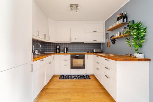 a kitchen with white cabinets and a wooden floor at Beautiful 2-bedroom apartment in Bergen