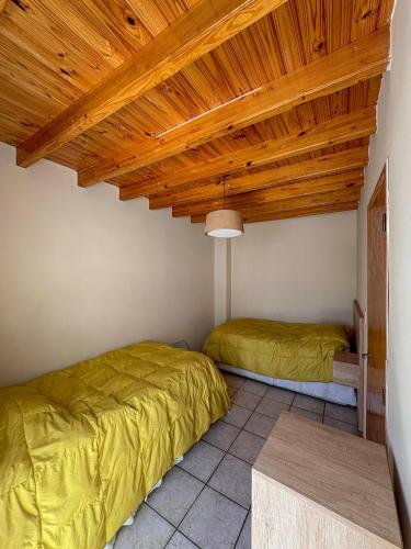a bedroom with two beds and a wooden ceiling at Edificio Mitre in Maipú