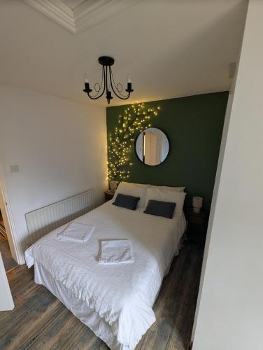 a bedroom with a white bed with a green wall at Harbour Street Nook in Whitstable