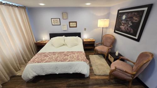 a bedroom with a bed and two chairs at Freyja Hostal Boutique - Café Bistró in Bogotá