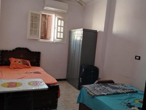 a bedroom with two beds and a cabinet and a window at شعبان in Beni Suef