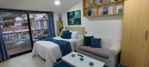 a bedroom with a bed and a couch and a window at Maradentro in Bueu