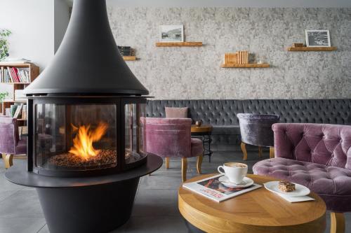 a fireplace in a living room with a table and chairs at Siglo Hotel by Keahotels in Siglufjörður