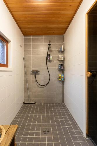 a shower with a hose in a bathroom with a tile floor at Vasko Luxurious Suites, Firefox in Rovaniemi