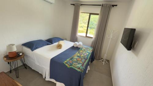 a bedroom with a bed with blue sheets and a television at Pousada do Lago in Guaramiranga