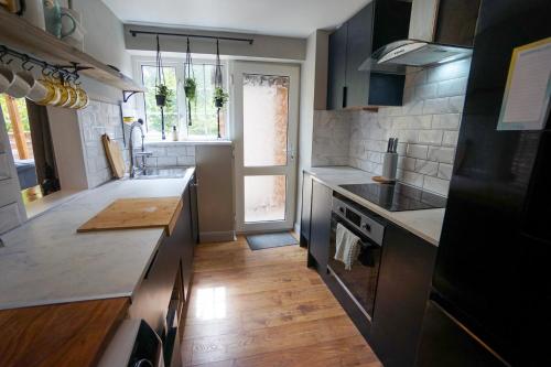 a kitchen with black cabinets and a wooden floor at Beautiful 2 Bed Home with Spacious Garden in Shephall