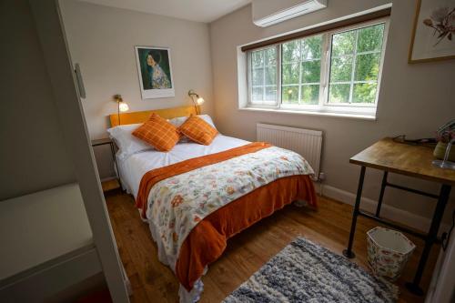 a bedroom with a bed with orange pillows and a window at Beautiful 2 Bed Home with Spacious Garden in Shephall