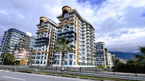 a large building with a palm tree in front of it at Cebeci tower in Mahmutlar