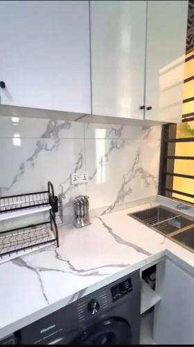 a kitchen with a white counter top with a dishwasher at Smartlinks apartments in Ikota