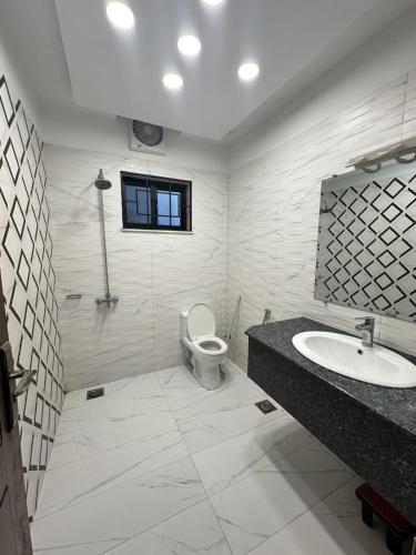 a white bathroom with a toilet and a sink at Comfort Family Villa Islamabad in Islamabad