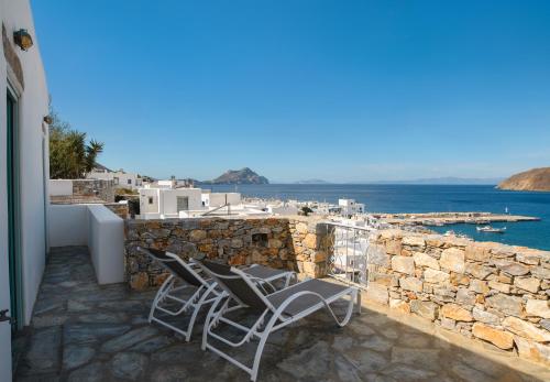 a balcony with two chairs and a stone wall at Amorgos Elegant Houses, Villa 3 in Aegiali
