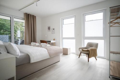 a white bedroom with a large bed and a chair at LaMiaCasa Green Large Loft City Close Green Area in Stuttgart