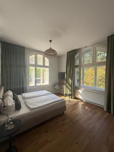 a bedroom with a large bed and two windows at Waldhotel Bad Essen in Bad Essen