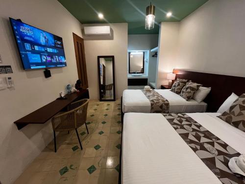 a hotel room with two beds and a flat screen tv at Hotel Boutique Santa Elena in Mérida
