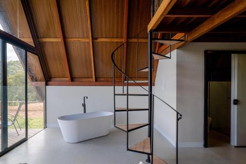 a bathroom with a bath tub and a spiral staircase at Serra e Sossego in Annitapolis