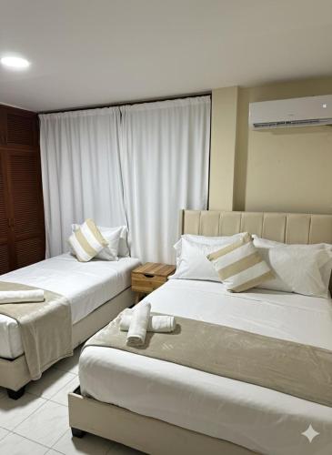 zwei Betten in einem Hotelzimmer mit weißen Möbeln in der Unterkunft Hotel ladymar cartagena in Cartagena de Indias