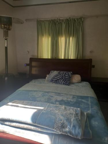 - un lit avec une couette bleue et une fenêtre dans l'établissement Chez La FAMILLE, à Kelaat-M'Gouna