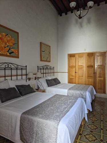 two beds in a room with white walls at Quinta María Hotel Boutique & Spa in Querétaro