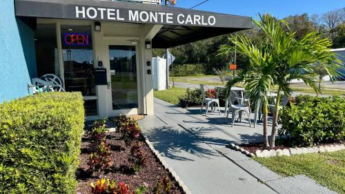 a hotel monkey carolla with chairs and a palm tree outside at Hotel Monte Carlo in Kissimmee