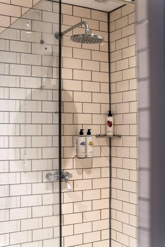 a shower with white tiled walls and a glass door at The Westgate in Winchester