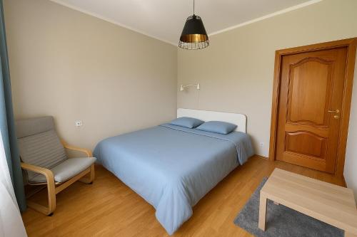 a bedroom with a blue bed and a chair at Garden View Apartment in Cēsis