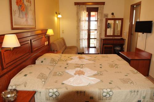 a bedroom with a large bed with a flowered spread at Hotel Athena in Kokkari