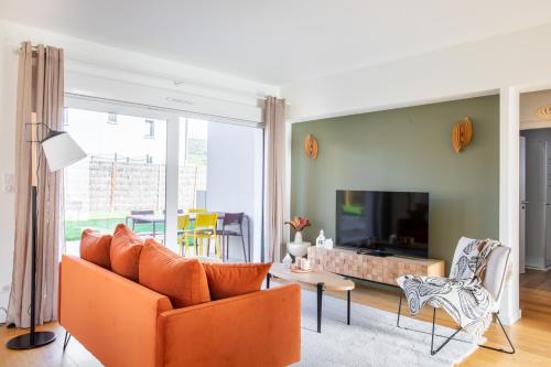 a living room with an orange couch and a tv at Rodern - Le Cocon des vignes in Rodern