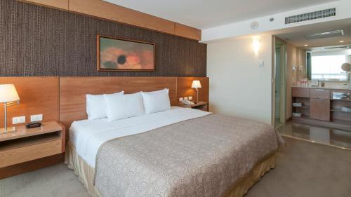 a hotel room with a large bed and a bathroom at Staybridge Suites Guadalajara Expo by IHG in Guadalajara