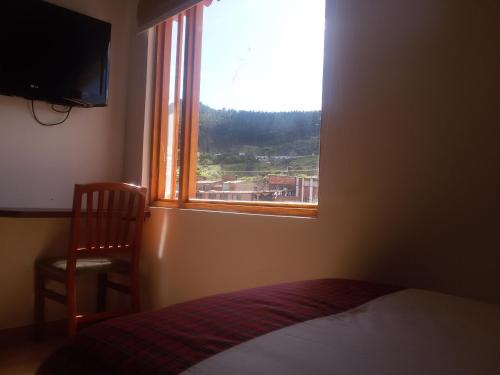 a bedroom with a window and a bed and a chair at Hotel Cacique Real in Zipaquirá