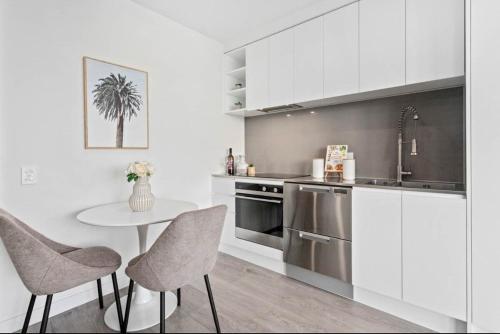 une cuisine avec des armoires blanches et une table et des chaises dans l'établissement CBD luxury Apartments Union green with Skytower View, à Auckland