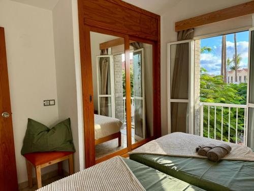 a bedroom with two beds and a window with a balcony at Oasis Lemon in Maspalomas