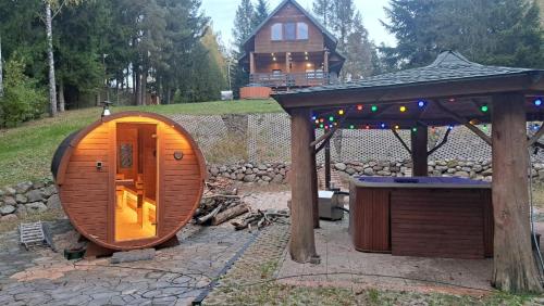una pequeña casa de hobbit de madera con un cenador en Dom na Mazurach Zatoka Leśna, en Wieniec