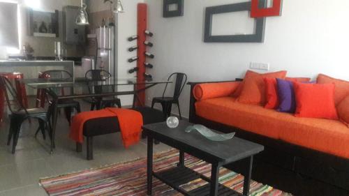 a living room with an orange couch and a table at DEPARTAMENTOS BOUTIQUE DE DISEÑADOR " TERRAZA 26" - Cochera- Vista a la Montaña- CANCELACIÓN GRATUITA- PAGARÁS EN EL ALOJAMIENTO in Mendoza