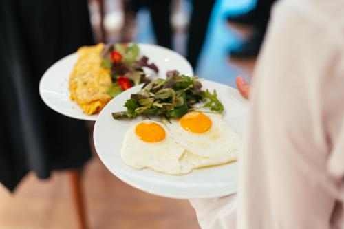 una persona che tiene due piatti di uova e verdure di Eternity Athens ad Atene