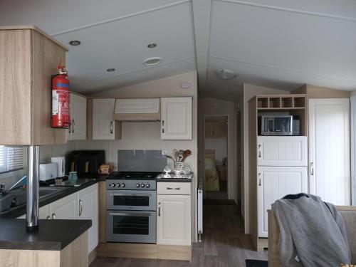 a kitchen with white cabinets and a stove top oven at Home from home Kingfisher caravan park in Skegness