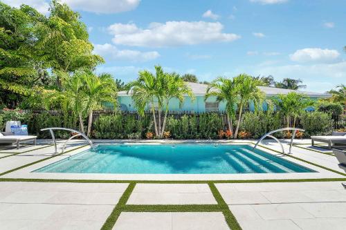 a swimming pool with palm trees and a building at New 2BR Bungalow Apartment #5 in West Palm Beach