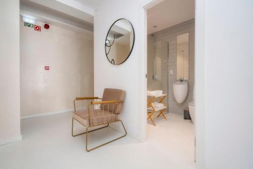 een badkamer met een spiegel aan de muur en een stoel bij Primavera House in Faro
