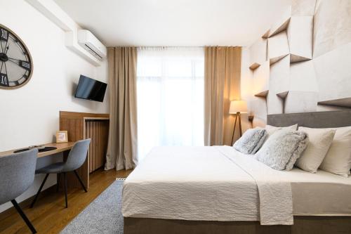 a bedroom with a bed and a desk and a clock at inJoy in Belgrade