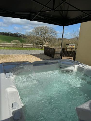 a hot tub with an umbrella in a yard at Meadowsweet Cottage Jacuzzi Edition in Saundersfoot