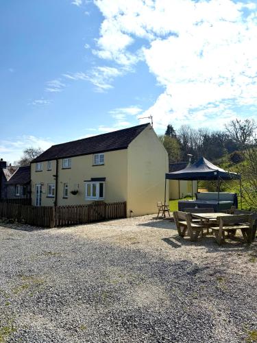 a house with a picnic table and an umbrella at Meadowsweet Cottage Jacuzzi Edition in Saundersfoot