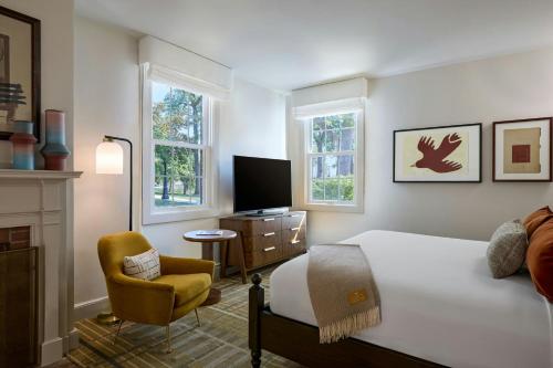 a bedroom with a bed and a chair and a television at Dearborn Inn, Autograph Collection in Dearborn